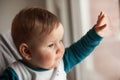 Portrait of cute baby boy looks at its reflection in the window Royalty Free Stock Photo