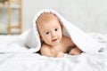 Adorable smiling baby boy lying on bed under white blanket Royalty Free Stock Photo