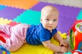 Portrait of cute baby boy lying on floor covered with multicolored soft mats in playroom. Adorable toddler kid smiling and playing Royalty Free Stock Photo