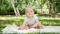 Portrait of cute baby boy sitting on grass under apple tree and holding red ripe apples. Concept of child development Royalty Free Stock Photo