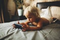 A portrait of a cute baby checking smartphone lying in a bed. Royalty Free Stock Photo