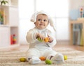 Portrait of a cute baby dressed in Easter bunny costume with eggs in hands
