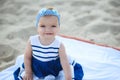 ÃÂ¡ute baby girl in nice striped dress and blue headband sitting on the sand smiling and showing her first teeth Royalty Free Stock Photo