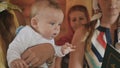 Portrait of cute baby in godmother hands during baptism ritual