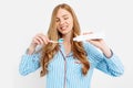 Portrait of a cute beautiful girl in pajamas and holding a tube of toothpaste and a toothbrush isolated on a white background, Royalty Free Stock Photo