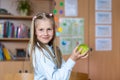 Portrait cute blond confident happy caucasian little blond little kid girl hold hand eating apple in classroom at lunch Royalty Free Stock Photo