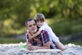 Portrait of cute blond girl hugging young father on pebbled rive Royalty Free Stock Photo