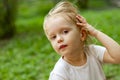 Portrait of cute blond toddler girl in a windy summer day trying to hold her fluterring hair
