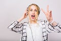 Portrait of cute blonde curly girl in headphones listening music with surprised face and dancing. Charming blue-eyed Royalty Free Stock Photo