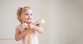 Portrait of a cute blue-eyed baby ballerina in pink hugging pointe shoes Royalty Free Stock Photo