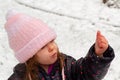 A girl in a pink knit hat holding snow in her hands Royalty Free Stock Photo