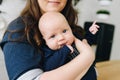 A portrait of cute blue eyed smiling baby hugged by his mum