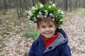 Portrait cute boy smiling, wreath of flowers on head in spring forest Royalty Free Stock Photo