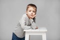 Portrait of a cute boy with standing at the chair in the photostudio