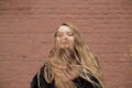 Portrait of cute brunette teen girl in black fur coat on the background of brown brick wall . Cosiness, fashion, style Royalty Free Stock Photo