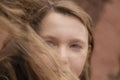 Portrait of cute brunette teen girl in black fur coat on the background of brown brick wall . Cosiness, fashion, style Royalty Free Stock Photo