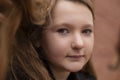 Portrait of cute brunette teen girl in black fur coat on the background of brown brick wall . Cosiness, fashion, style Royalty Free Stock Photo