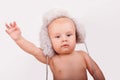 Portrait of cute caucasian baby nine month year old with blue eyes wearing a furry hat on a light background holding Royalty Free Stock Photo