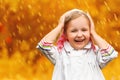 Portrait of a cute charming laughing little girl standing in autumn park in the rain. Royalty Free Stock Photo