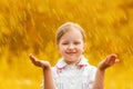 Portrait of a cute charming little girl standing in autumn park in the rain. The child stretched out his hands and collects the