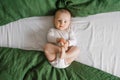 Portrait of a cute charming smiling laughing Caucasian white boy of six months old lying on a bed and looking at the camera Royalty Free Stock Photo