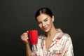 Portrait of cute cheerful glamorous female with red coffee mug on black background