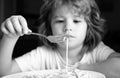 Portrait of a cute child boy eating pasta, spaghetti. Close up caucasian kids face. Closeup head of funny kid. Royalty Free Stock Photo