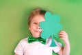 Portrait Cute Child boy holding paper clover shamrock on green background. Irish St. Patrick's Day