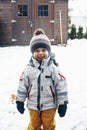 Portrait of a cute contented todler boy in winter clothes outdoors in the snow. Winter time, winter fun, happy childhood. Vertical Royalty Free Stock Photo