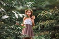 Portrait of cute curious little girl in a straw hat holding a magnifier and walking through tropics forest. The