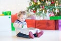 Portrait of a cute curly toddler girl opening her Christmas present Royalty Free Stock Photo