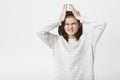 Portrait of cute european girl who suffers headache, holding her hands on had and clenches teeth. Female student