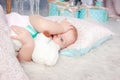 Portrait of cute european little blonde princess girl with bear in beautiful dress lying on the floor in decorated studio in Royalty Free Stock Photo