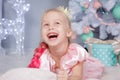 Portrait of cute european little blonde princess girl with crown in beautiful dress in decorated studio in christmas location with Royalty Free Stock Photo