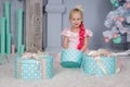 Portrait of cute european little blonde princess girl with crown in beautiful dress sitting on the floor and opening gifts in Royalty Free Stock Photo