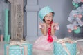 Portrait of cute european little blonde princess girl with crown in beautiful dress sitting on the floor and opening gifts in Royalty Free Stock Photo