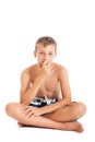 Portrait of a cute european teen boy wearing swimming shorts. A boy sitting on the floor. Royalty Free Stock Photo