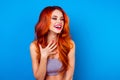 Portrait of cute excited attractive girl with long ginger fair hair laughing while standing on blue background Royalty Free Stock Photo