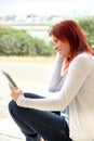 Portrait of a cute expressive redhead woman reading information on its touch pad Royalty Free Stock Photo