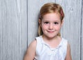 Portrait of a cute four year smiling blonde girl in white dress