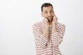 Portrait of cute friendly european man in casual striped pullover, holding cheeks with palms and making faces, looking Royalty Free Stock Photo