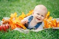 Portrait of cute funny adorable blond Caucasian baby boy with blue eyes in tshirt and jeans romper lying on grass field meadow Royalty Free Stock Photo