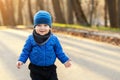 Portrait of cute funny caucasian toddler boy in blue jacket and hat enjoying walking at autumn park or forest during sunset with Royalty Free Stock Photo