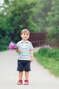 Portrait of a cute funny little boy toddler standing in the forest field meadow with dandelion flowers in hands Royalty Free Stock Photo