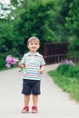 Portrait of a cute funny little boy toddler standing in the forest field meadow with dandelion flowers in hands Royalty Free Stock Photo