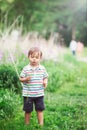 Portrait of a cute funny little boy toddler standing in the forest field meadow with dandelion flowers in hands Royalty Free Stock Photo