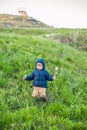 Portrait of a cute funny little boy toddler standing in the forest field meadow with dandelion flowers in hands and blowing them Royalty Free Stock Photo