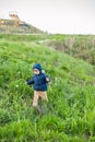 Portrait of a cute funny little boy toddler standing in the forest field meadow with dandelion flowers in hands and blowing them Royalty Free Stock Photo