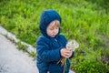 Portrait of a cute funny little boy toddler standing in the forest field meadow with dandelion flowers in hands and blowing them Royalty Free Stock Photo