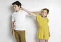 Portrait of cute girl and boy on studio white background conflit each other